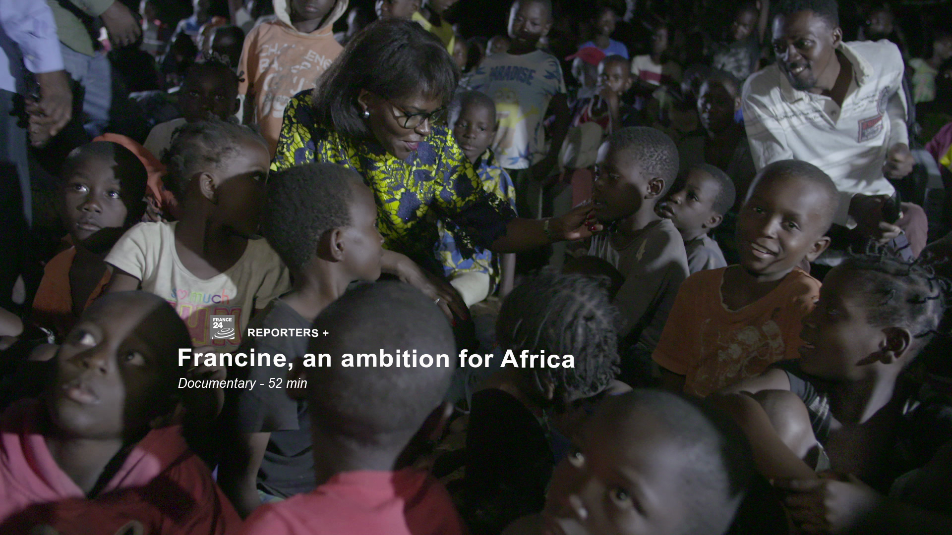 A woman surrounded by a group of attentive children who look at her. Text overlay reads: "Reporters+ Francine, an ambition for Africa. Documentary - 52 min." The scene is dimly lit, suggesting an intimate setting, possibly during an evening meeting or gathering.